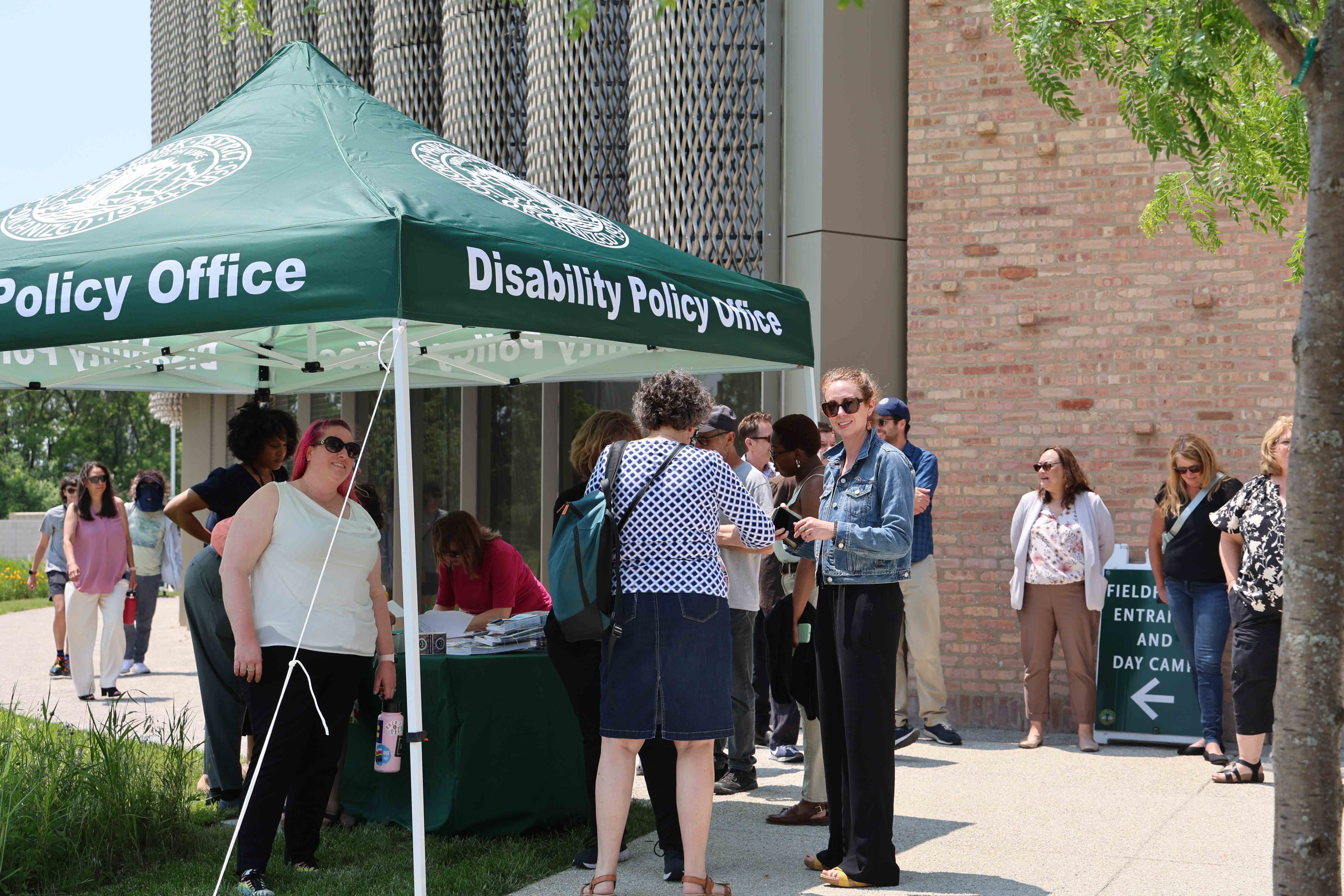 People gather at an outdoor Disability Policy Office tent.